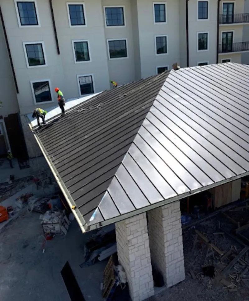 Crew installing standing seam metal roof panels on a commercial project in Iowa Park